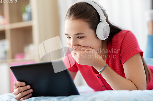 Image of girl in headphones listening to music on tablet pc