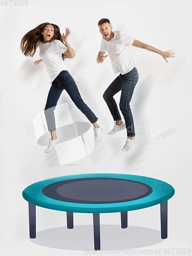 Image of Colorful drawing in cartoon style collaged with portrait of young caucasian couple jumping on trampoline high
