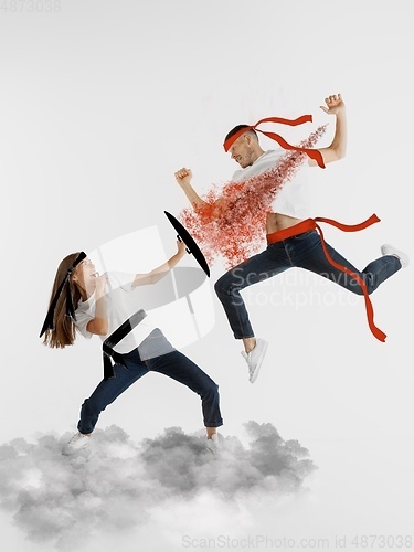 Image of Colorful drawing in cartoon style collaged with portrait of young caucasian couple fighting like ninjas on cloud in flight