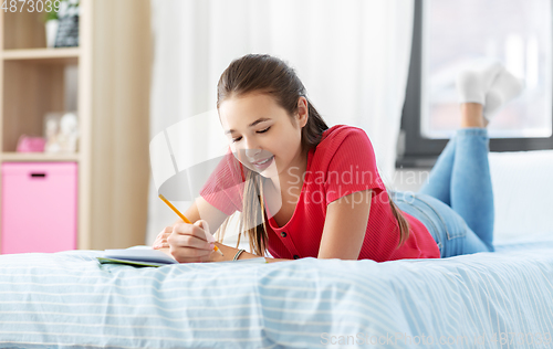 Image of teenage girl writing to diary at home