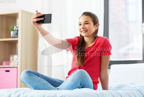 Image of happy girl with smartphone taking selfie at home