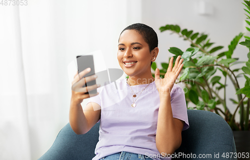 Image of woman with smartphone having video call at home