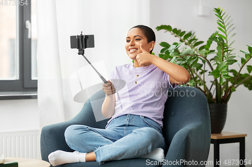 Image of happy african american woman taking selfie at home