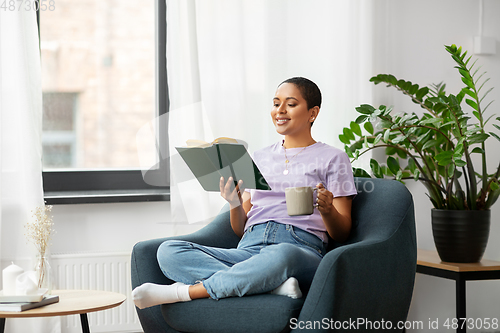 Image of happy african american woman reading book at home