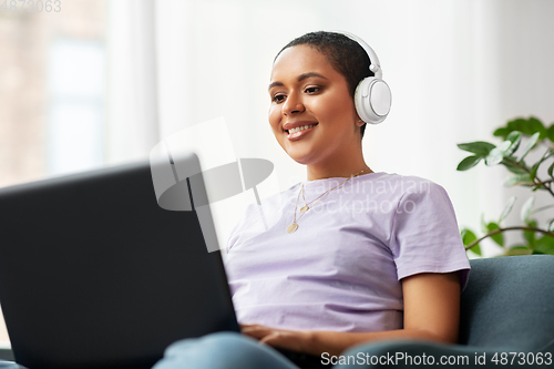 Image of woman with laptop listening to music at home