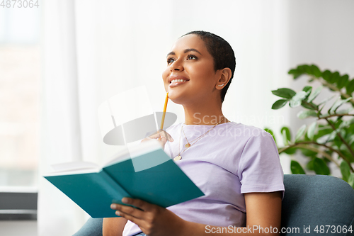 Image of happy african american woman with diary at home