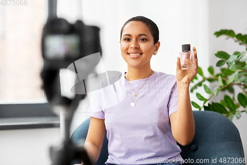 Image of female beauty blogger with camera and perfume