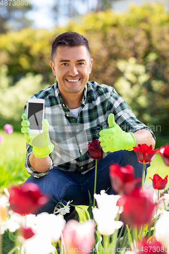 Image of man with phone showing thumbs up at flowers garden