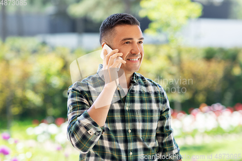 Image of happy man calling on smartphone at summer garden