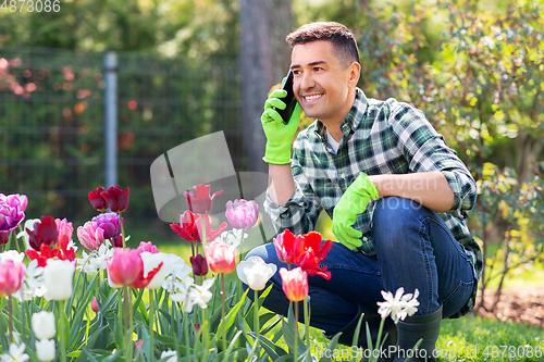 Image of man with flowers calling on smartphone at garden