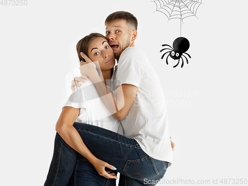 Image of Colorful drawing in cartoon style collaged with portrait of young caucasian couple. Woman holding her man that scared of spider