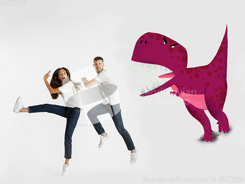 Image of Colorful drawing in cartoon style collaged with portrait of young caucasian couple running from dinosaur