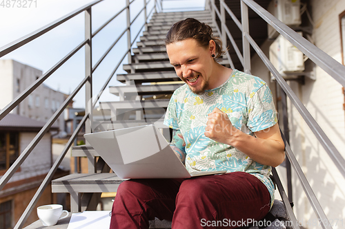 Image of Young man, businessman working, studying outdoors, looking on computer screen, monitor. Copyspace.