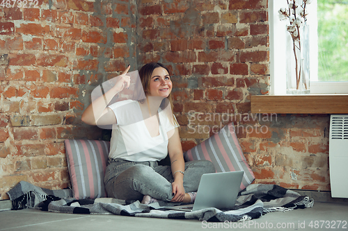 Image of Young woman, businesswoman working or studying at home with laptop near window. Attented, concentrated. Copyspace.