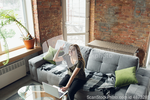 Image of Young woman, businesswoman working or studying at home, looking on computer screen, monitor. Attented, concentrated. Copyspace. Top view.