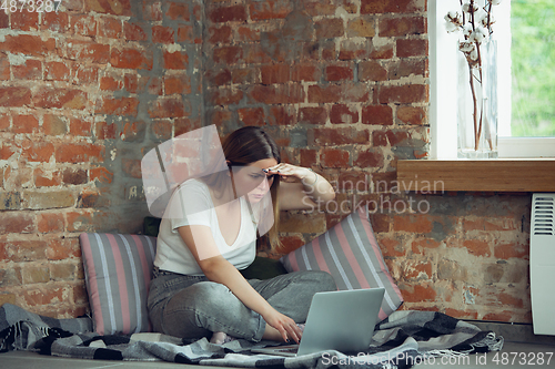 Image of Young woman, businesswoman working or studying at home with laptop near window. Attented, concentrated. Copyspace.