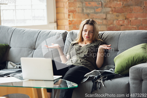 Image of Young woman, businesswoman working or studying at home with laptop sitting on sofa. Attented, concentrated. Copyspace.