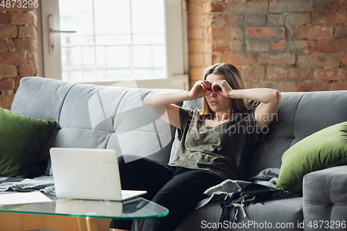 Image of Young woman, businesswoman working or studying at home with laptop sitting on sofa. Attented, concentrated. Copyspace.