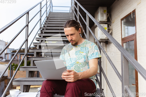 Image of Young man, businessman working, studying outdoors, looking on computer screen, monitor. Copyspace.