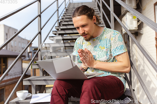 Image of Young man, businessman working, studying outdoors, looking on computer screen, monitor. Copyspace.