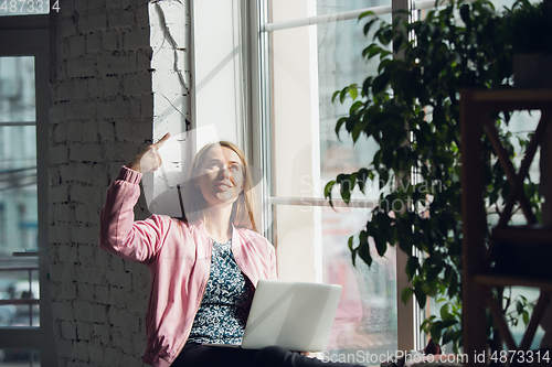 Image of Young woman, businesswoman working or studying at home with laptop near window. Attented, concentrated. Copyspace.