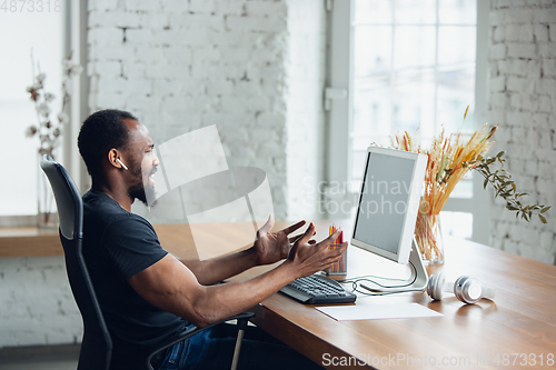 Image of Young man, businessman working in office, looking on blank black computer screen, monitor. Copyspace.