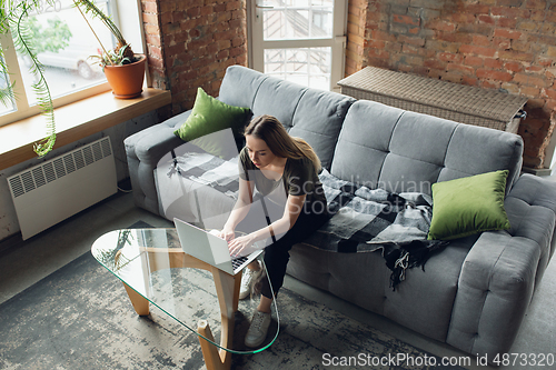 Image of Young woman, businesswoman working or studying at home, looking on computer screen, monitor. Attented, concentrated. Copyspace. Top view.