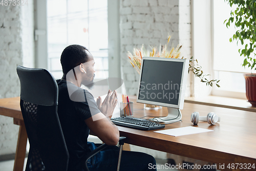 Image of Young man, businessman working in office, looking on blank black computer screen, monitor. Copyspace.