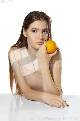 Image of Healthcare. Beautiful young woman with orange over white background. Cosmetics and makeup, natural and eco treatment, skin care.