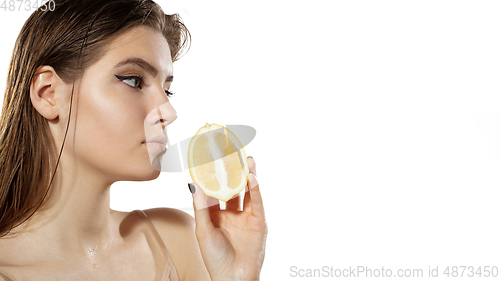 Image of Vitamins. Beautiful young woman with lemon slice over white background. Cosmetics and makeup, natural and eco treatment, skin care. Flyer with copyspace.