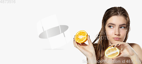 Image of Youth secrets. Close up of beautiful young woman with lemon and orange slices over white background. Cosmetics and makeup, natural and eco treatment, skin care. Flyer with copyspace.