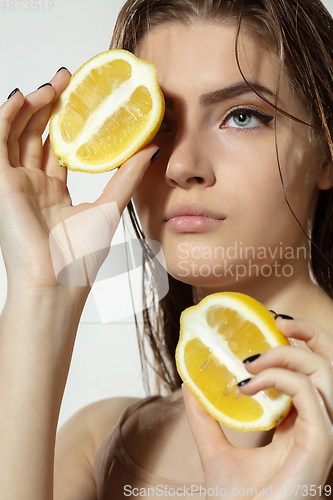 Image of Youth secrets. Close up of beautiful young woman with lemon slices over white background. Cosmetics and makeup, natural and eco treatment, skin care.