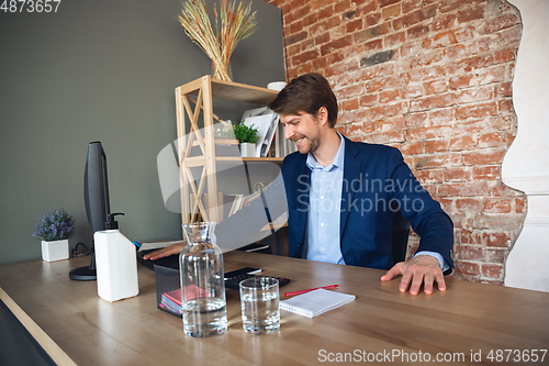 Image of Young man, manager, team led return to work in his office after quarantine, feels happy and inspired