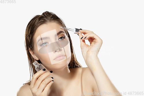 Image of Youth secrets. Close up of beautiful young woman with serum, essential oil over white background. Cosmetics and makeup, natural and eco treatment, skin care.