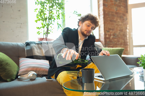 Image of Young man in pajama and jacket working on a computer, laptop. Remote office during coronavirus, fun and comfortable work in underpants