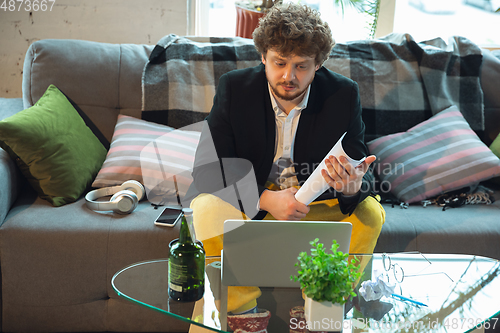 Image of Young man in pajama and jacket working on a computer, laptop. Remote office during coronavirus, fun and comfortable work in underpants