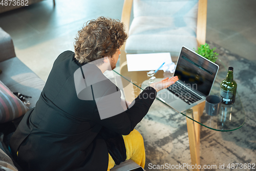 Image of Young man in pajama and jacket working on a computer, laptop. Remote office during coronavirus, fun and comfortable work in underpants