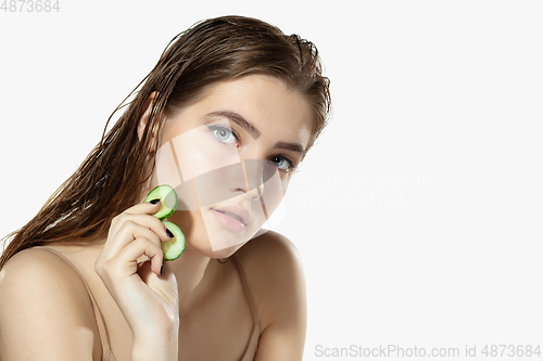 Image of Youth secrets. Close up of beautiful young woman with cucumber slices over white background. Cosmetics and makeup, natural and eco treatment, skin care.