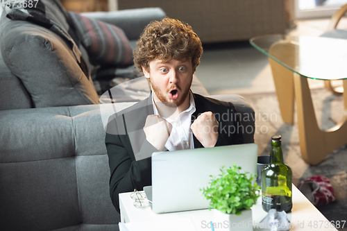 Image of Young man without pants but in jacket working on a computer, laptop. Remote office during coronavirus, fun and comfortable work in underpants