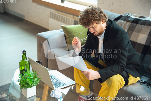 Image of Young man in pajama and jacket working on a computer, laptop. Remote office during coronavirus, fun and comfortable work in underpants