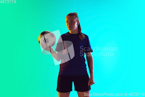 Image of Female soccer, football player holding ball, posing confident isolated on gradient background. Copyspace.