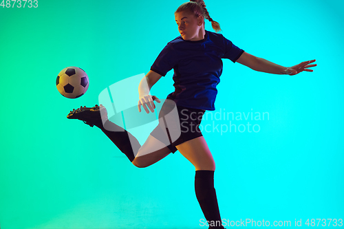 Image of Female soccer, football player kicking ball, training in action and motion with bright emotions isolated on gradient background