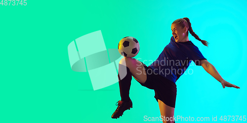 Image of Female soccer, football player kicking ball, training in action and motion with bright emotions isolated on gradient background. Flyer with copyspace.