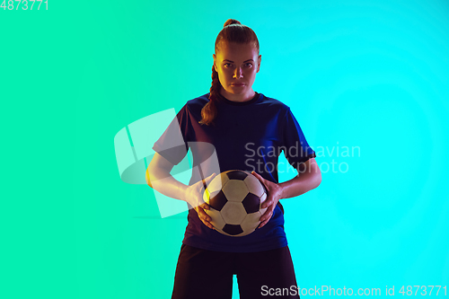 Image of Female soccer, football player holding ball, posing confident isolated on gradient background. Copyspace.