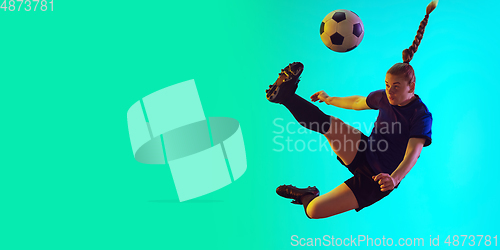 Image of Female soccer, football player kicking ball, training in action and motion with bright emotions isolated on gradient background. Flyer with copyspace.