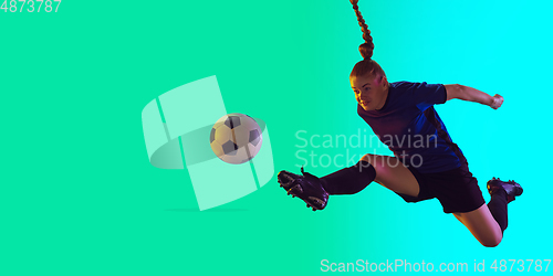 Image of Female soccer, football player kicking ball, training in action and motion with bright emotions isolated on gradient background. Flyer with copyspace.