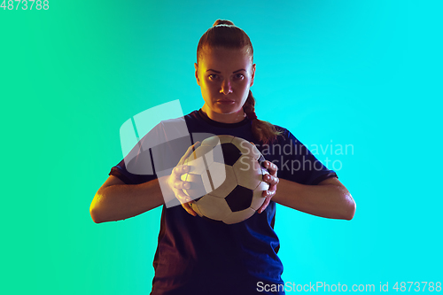 Image of Female soccer, football player holding ball, posing confident isolated on gradient background. Copyspace.