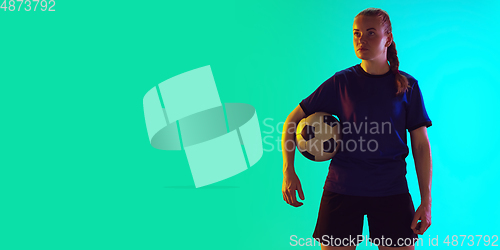 Image of Female soccer, football player holding ball, posing confident isolated on gradient background. Flyer with copyspace.