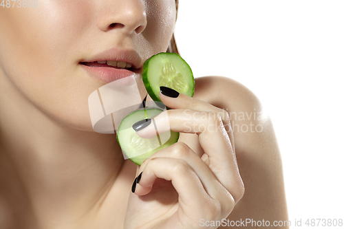 Image of Close up of beautiful young woman with cucumber slices over white background. Cosmetics and makeup, natural and eco treatment, skin care.