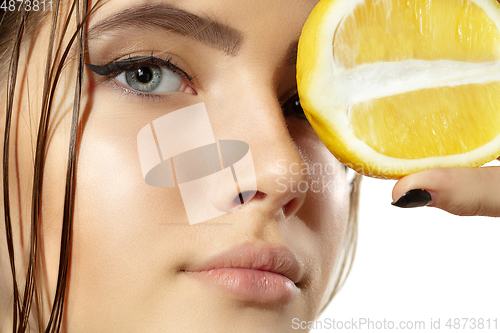 Image of Close up of beautiful young woman with lemon slices over white background. Cosmetics and makeup, natural and eco treatment, skin care.